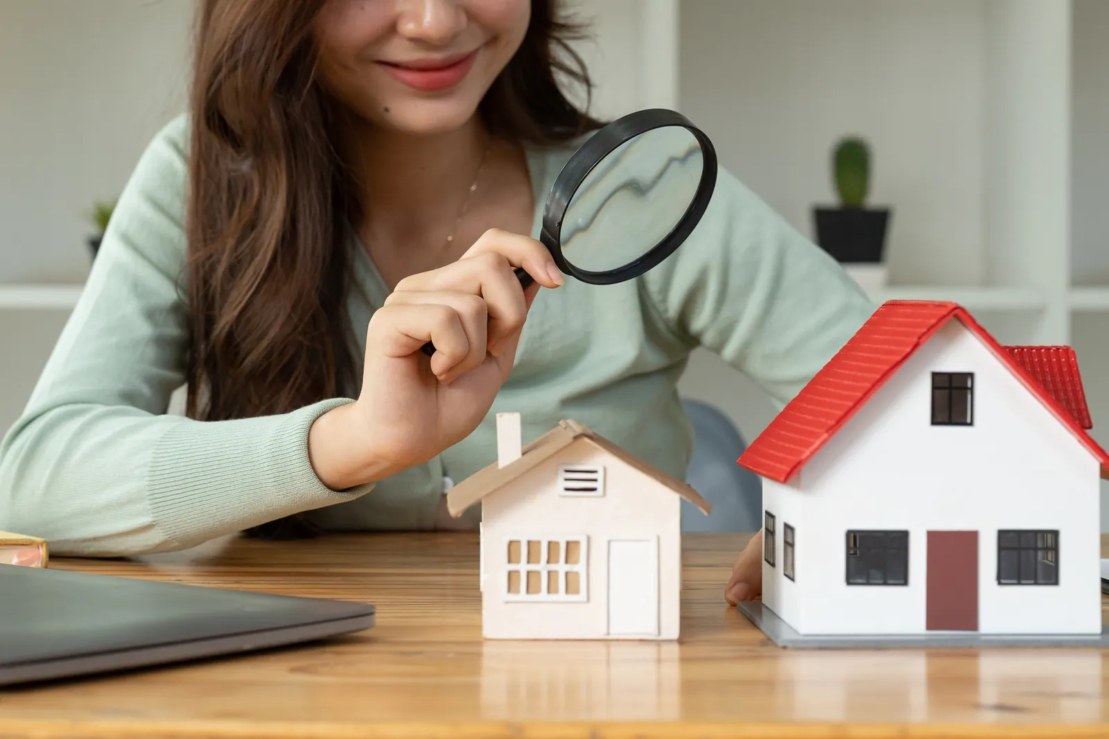 Woman inspecting a model house with a magnifying glass