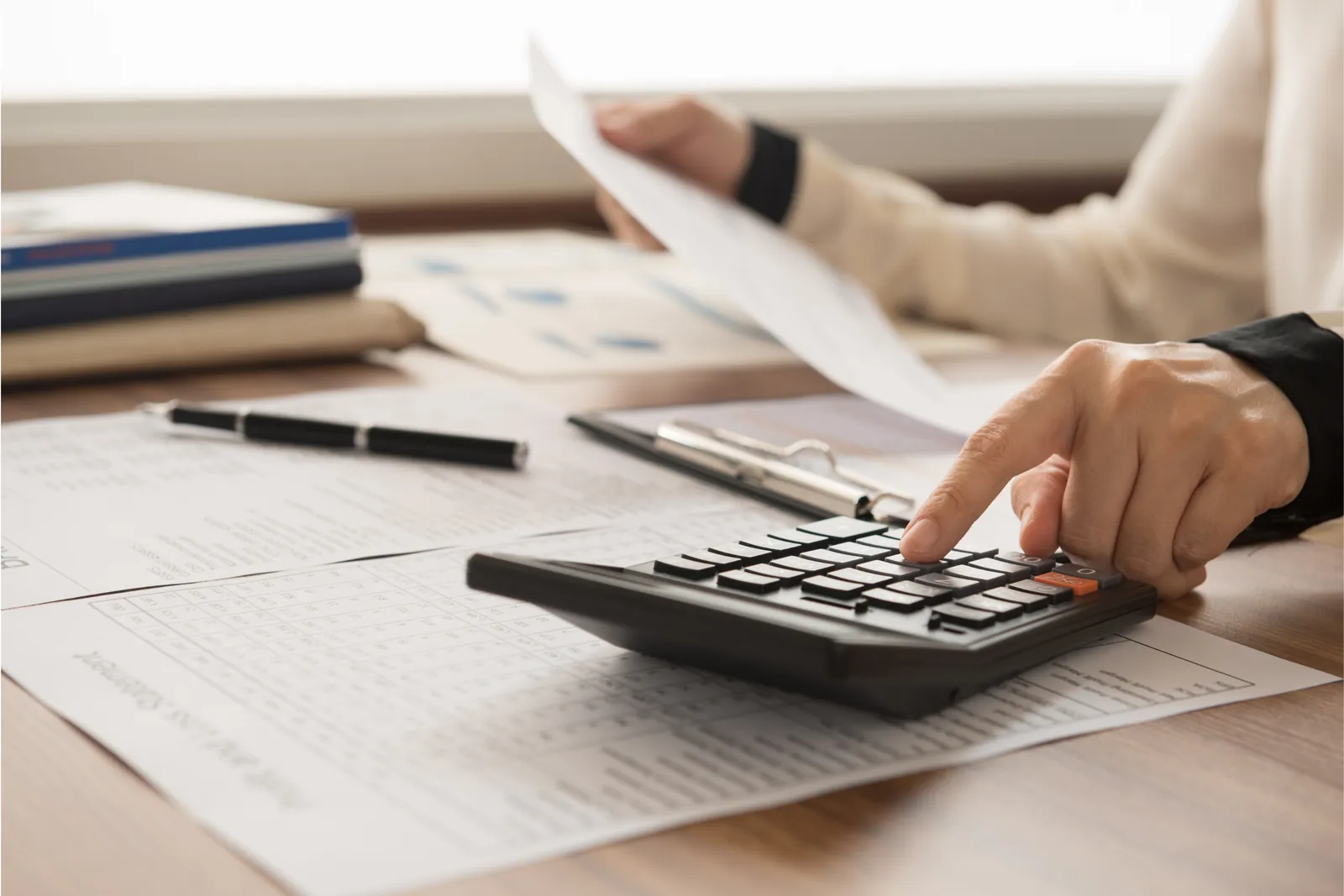 Homebuyer working through costs on a calculator with paperwork