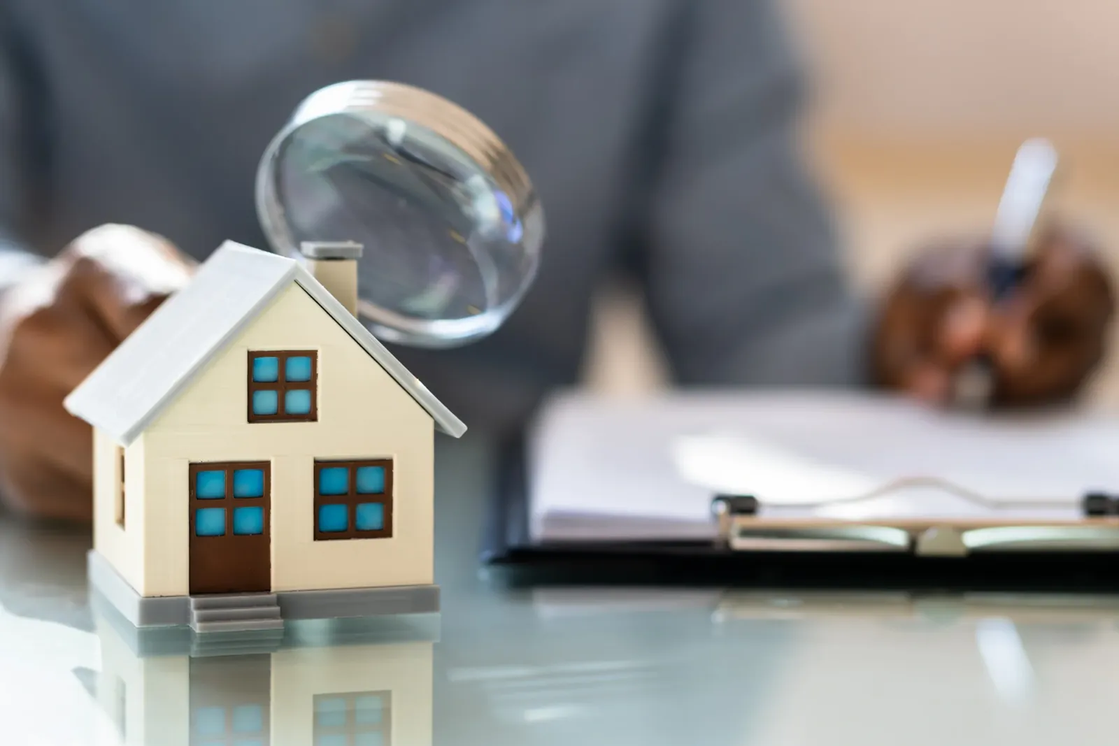 Appraiser reviewing documents next to a model house and magnifying glass