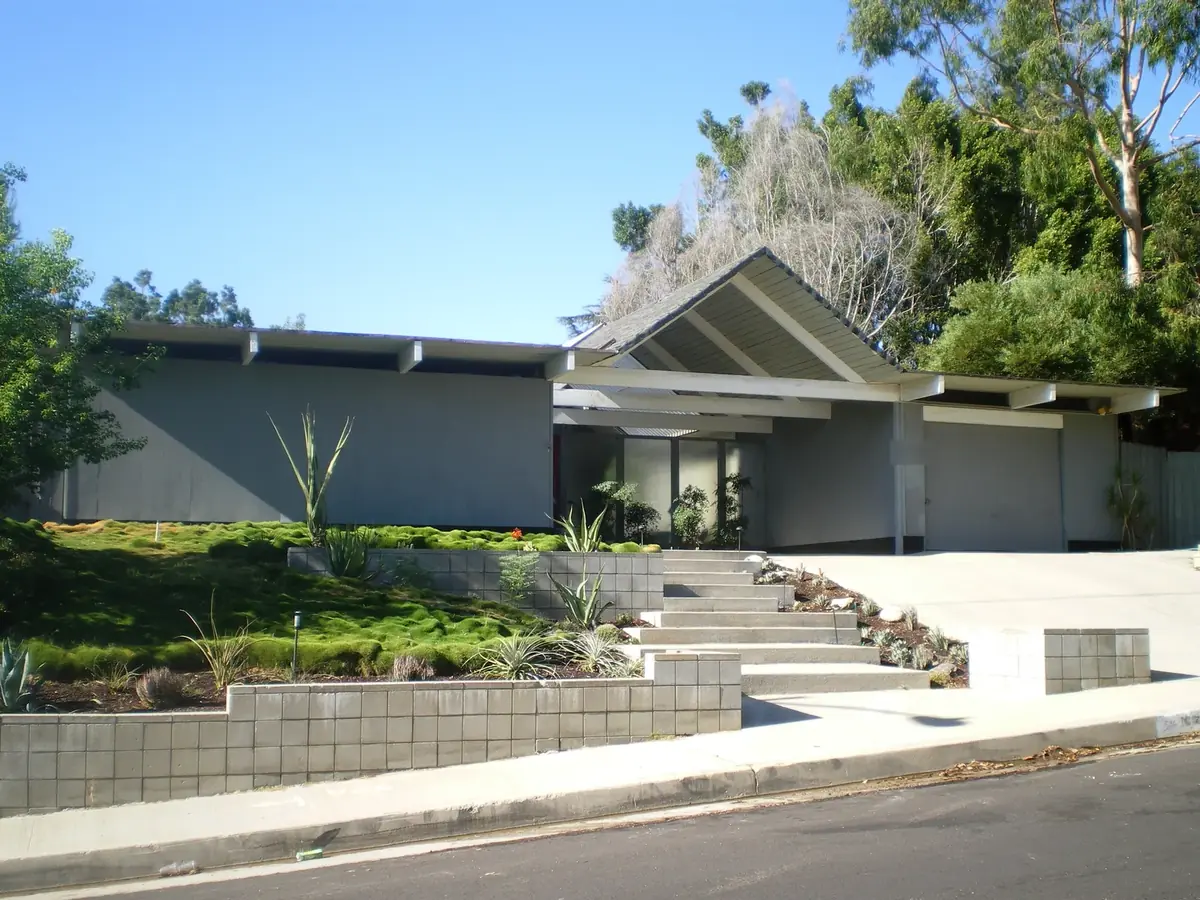 Mid-century Eichler home in Granada Hills with a low-pitched roof, glass entry, attached garage and a terraced succulent garden behind a block retaining wall