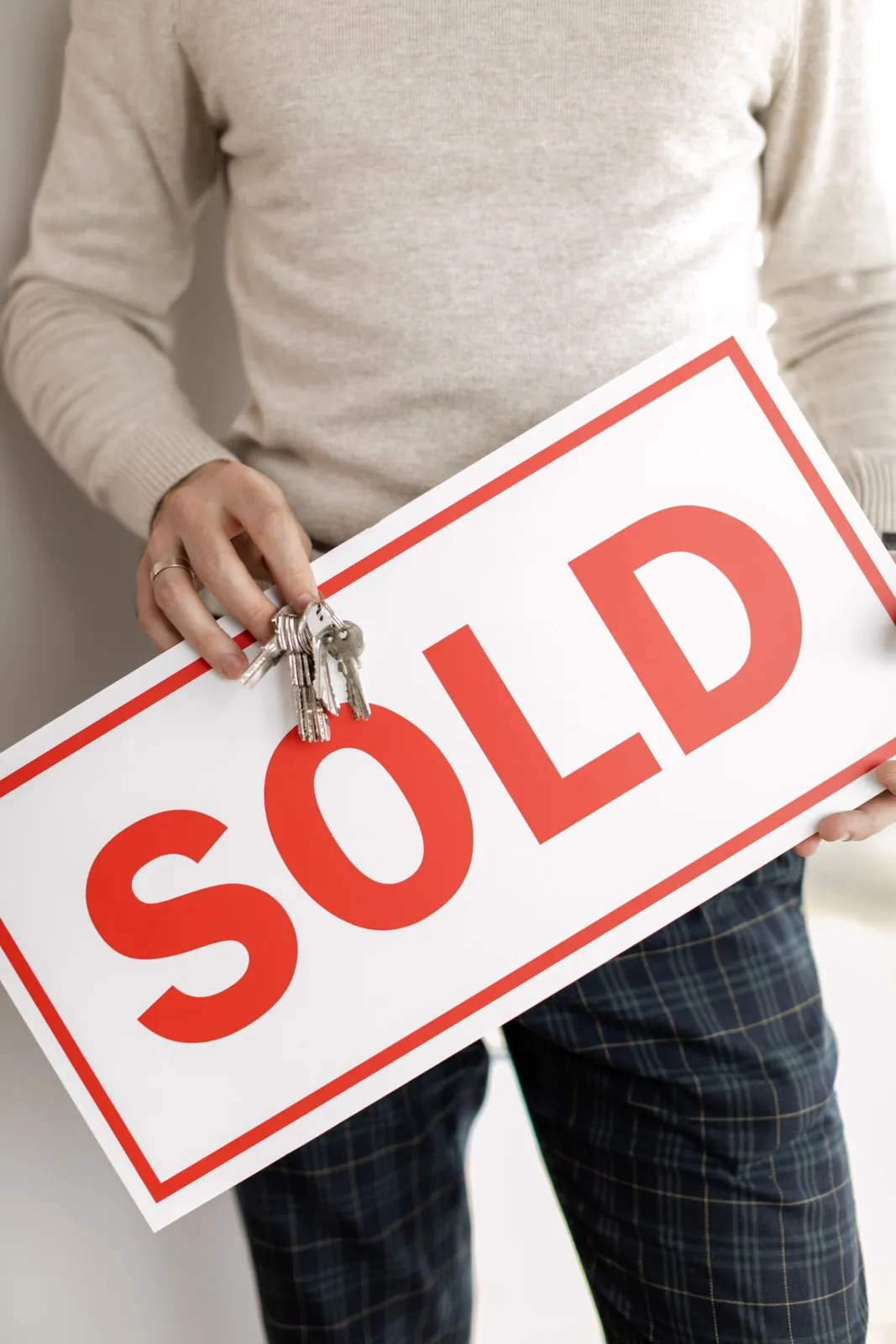 Person holding a red Sold sign