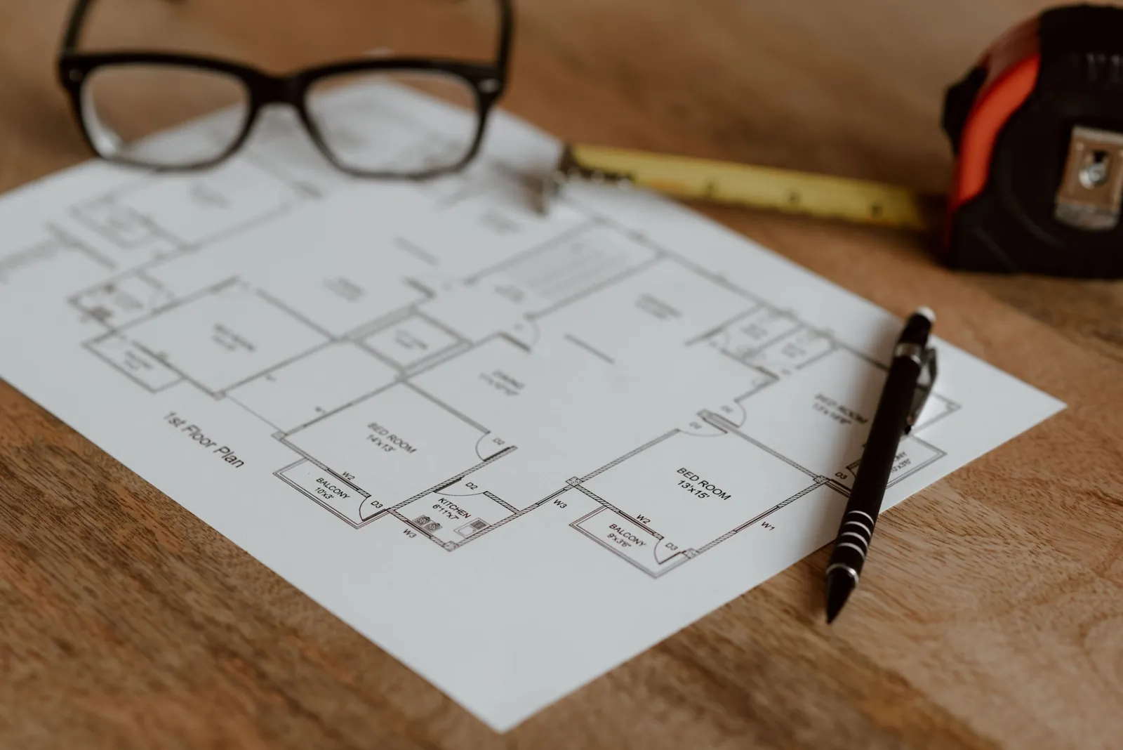 Floor plan drawing with glasses, pen and tape measure