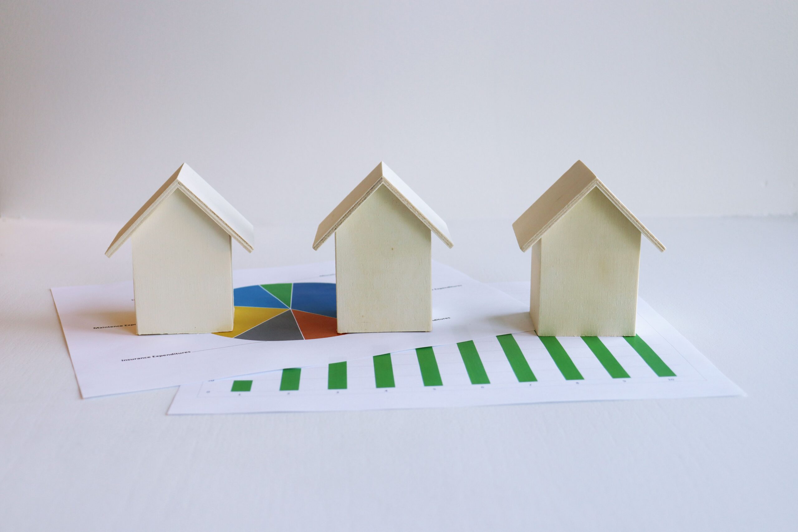 Three white model houses standing on a printed bar chart