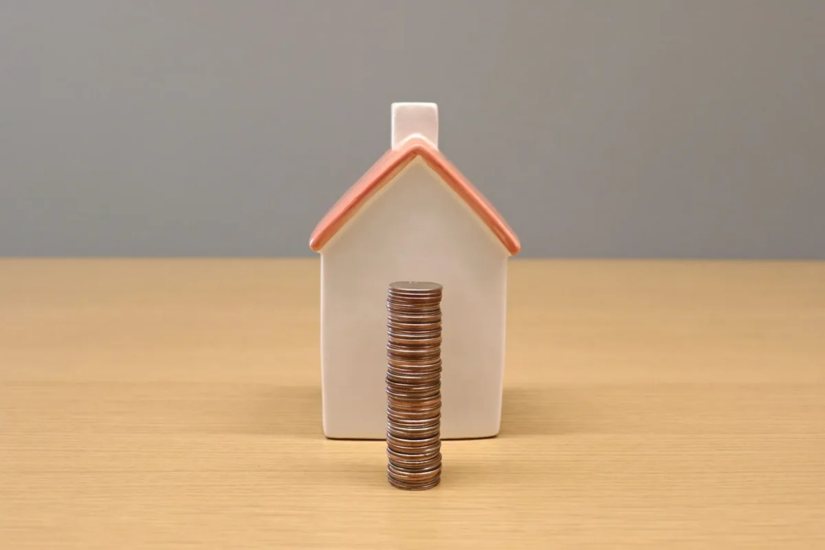 Model house with a stack of coins in front of it