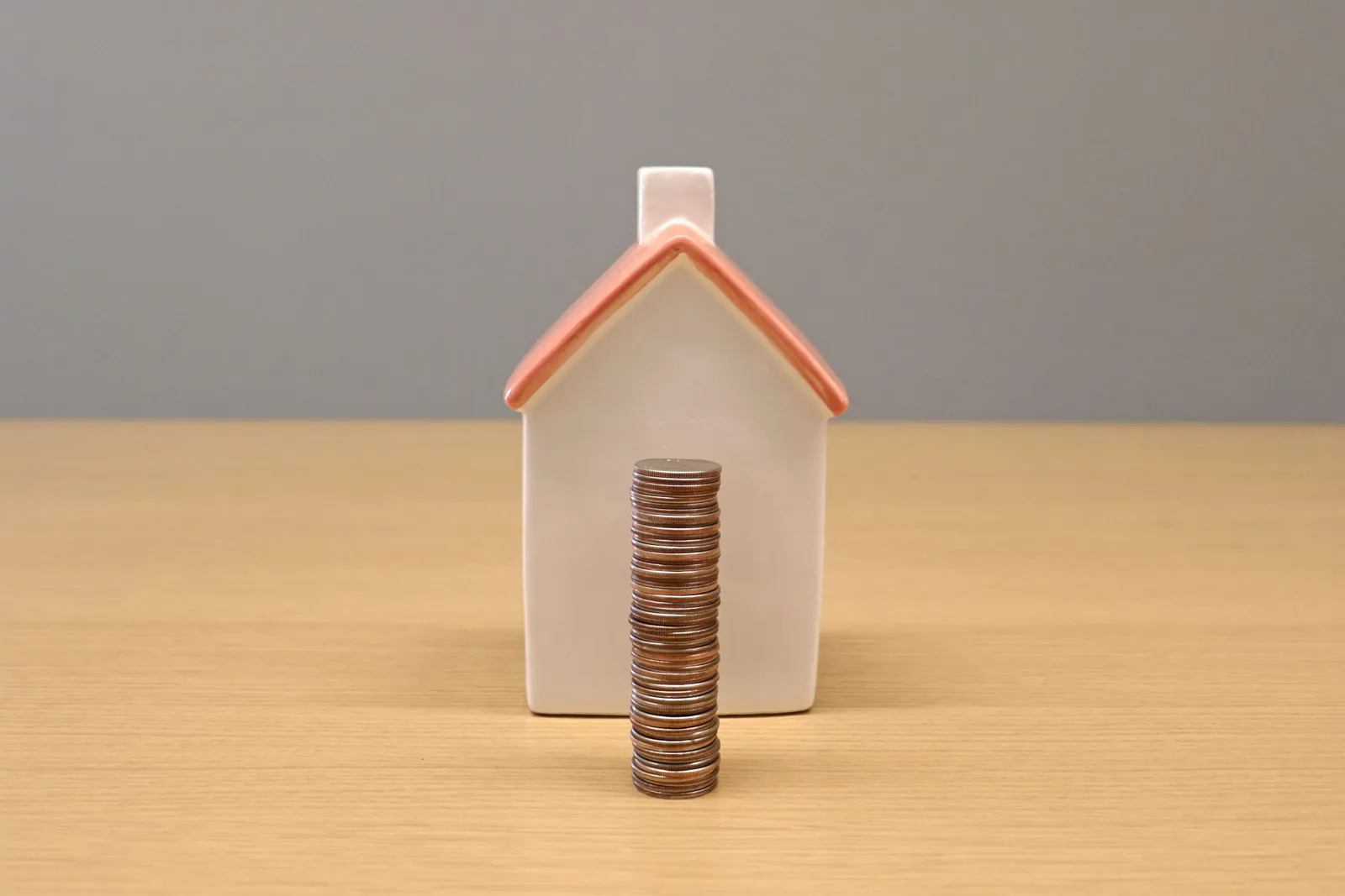 Model house with a stack of coins in front of it