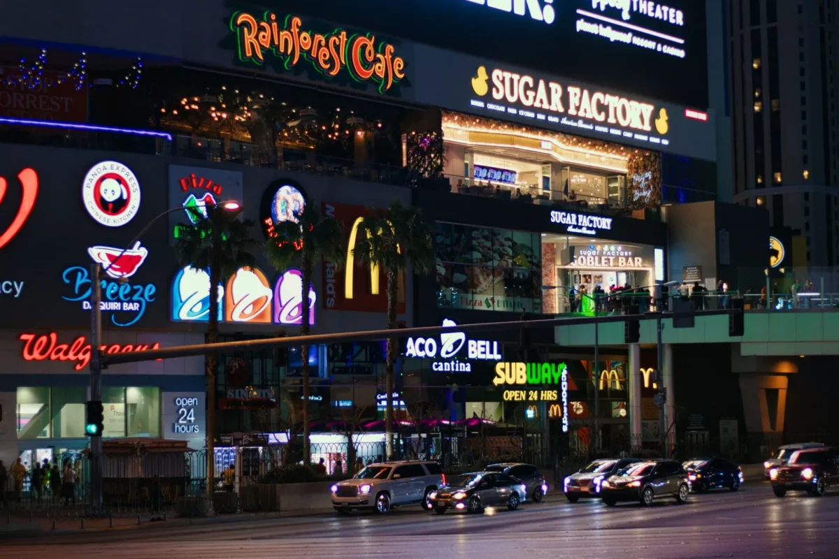 Neon-lit restaurant and shop signs on a city street at night