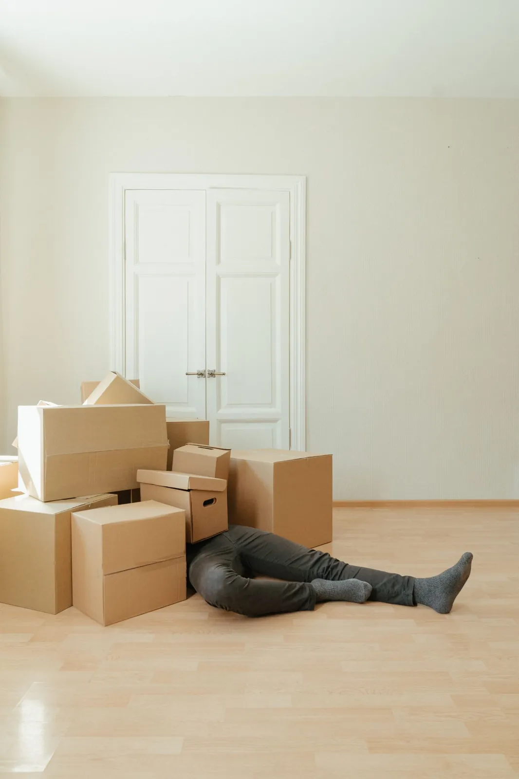 Person lying on the floor beside moving boxes in an empty room