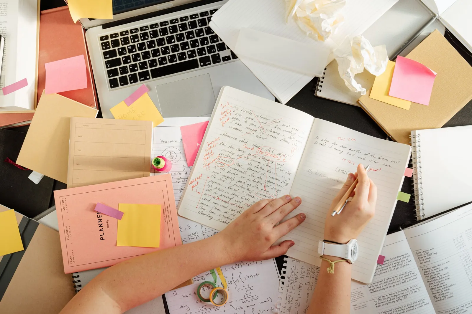 Person reviewing paperwork and sticky notes at a cluttered desk