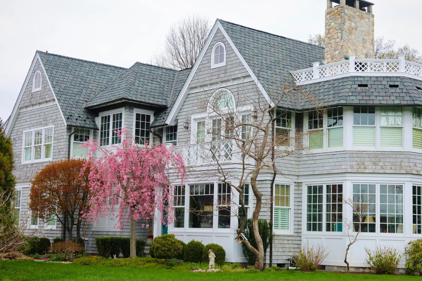 Large gray Victorian-style home with a blooming front yard