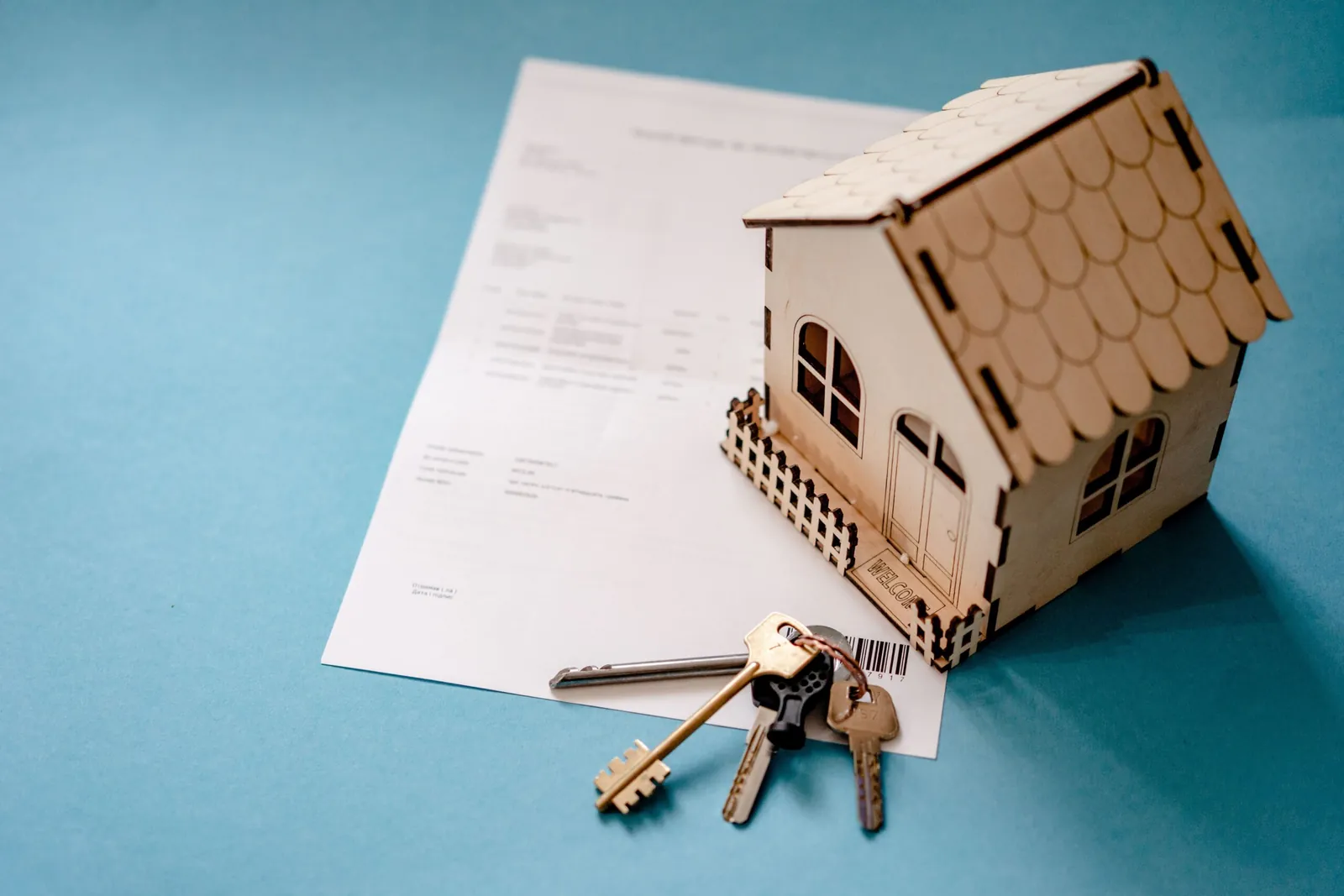 Wooden model house and keys on a document