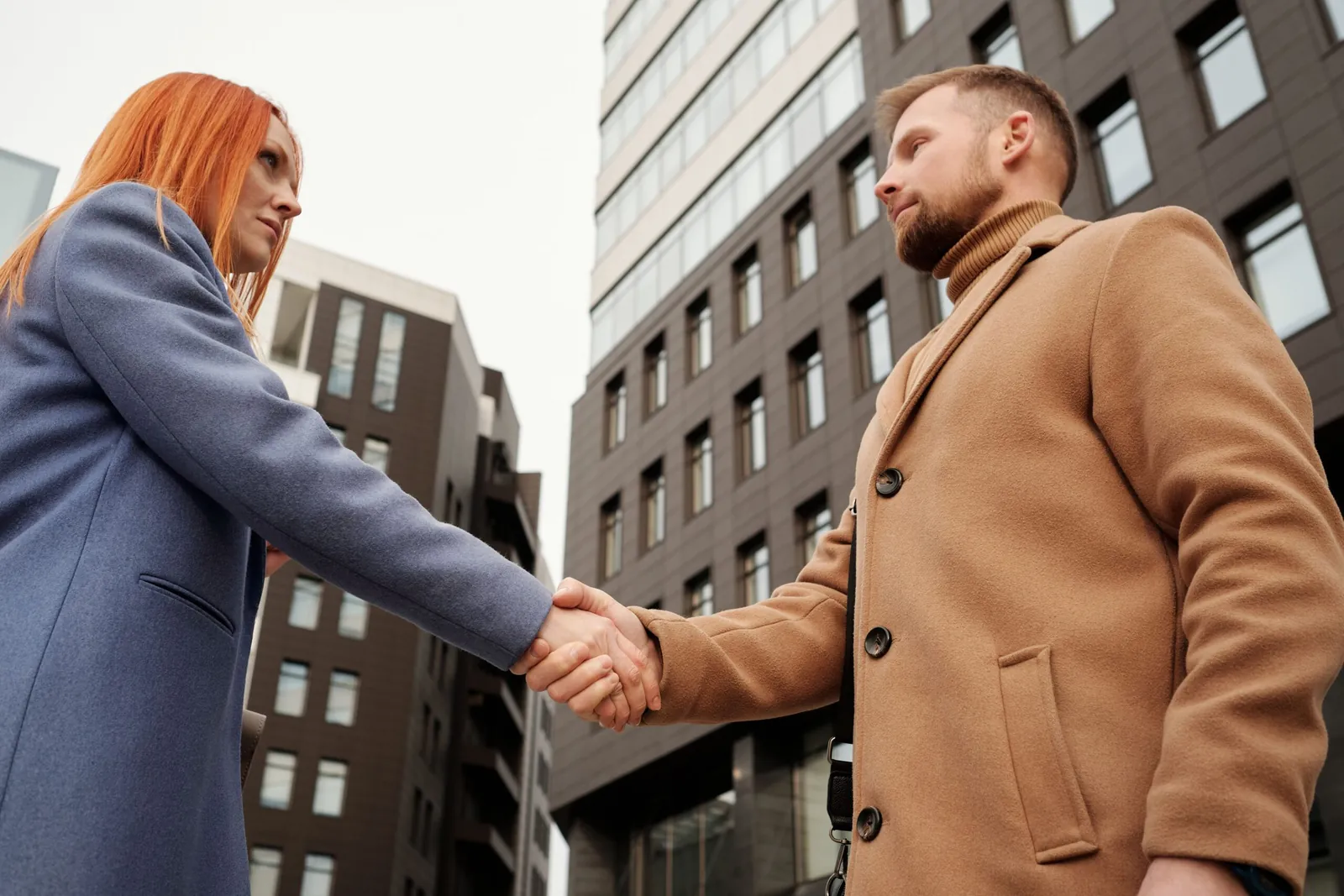 Two people shaking hands outside an office building