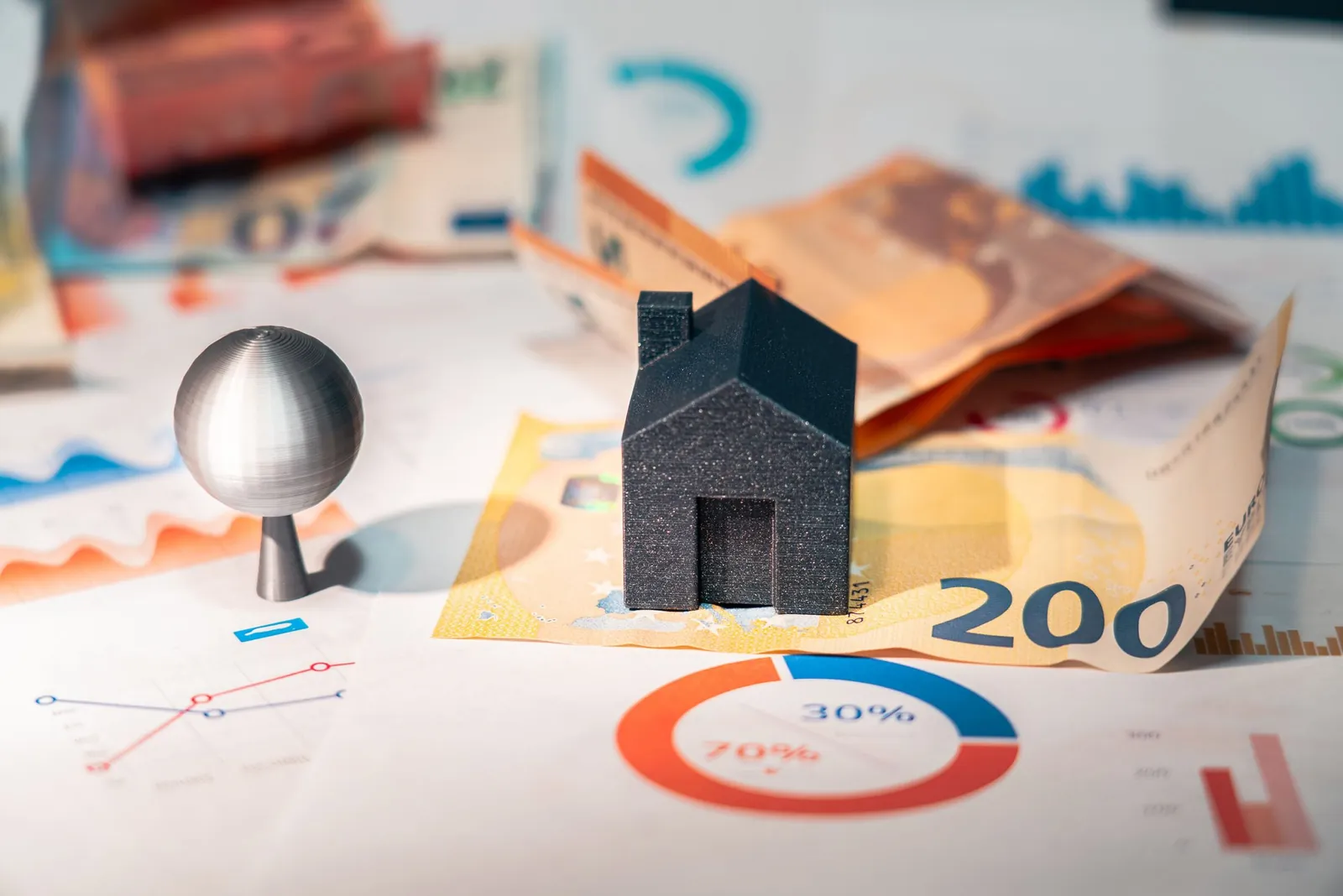 Black model house and euro notes on printed sales charts