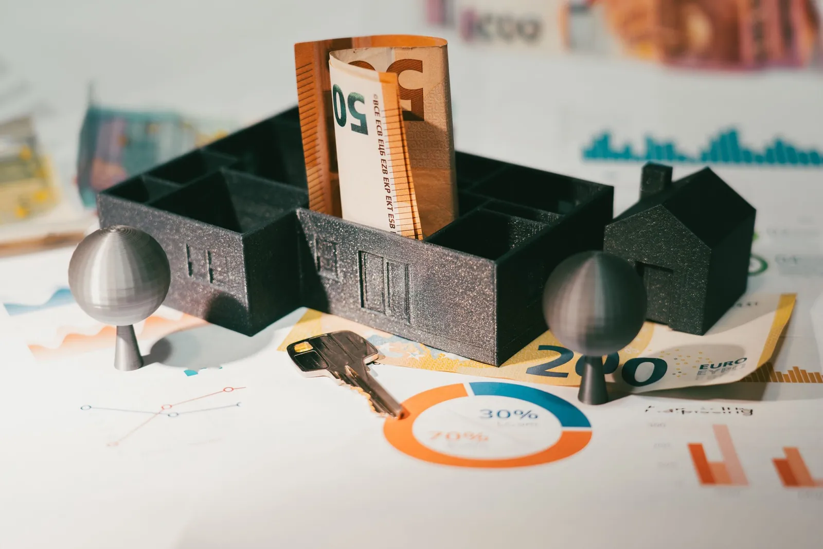 Model house filled with rolled cash on printed charts