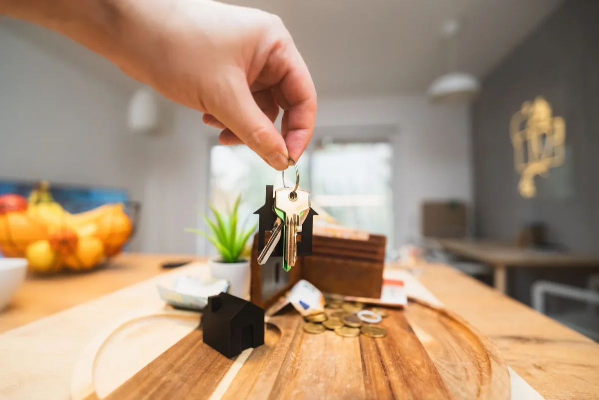 Hand dropping a coin into a small wooden house bank