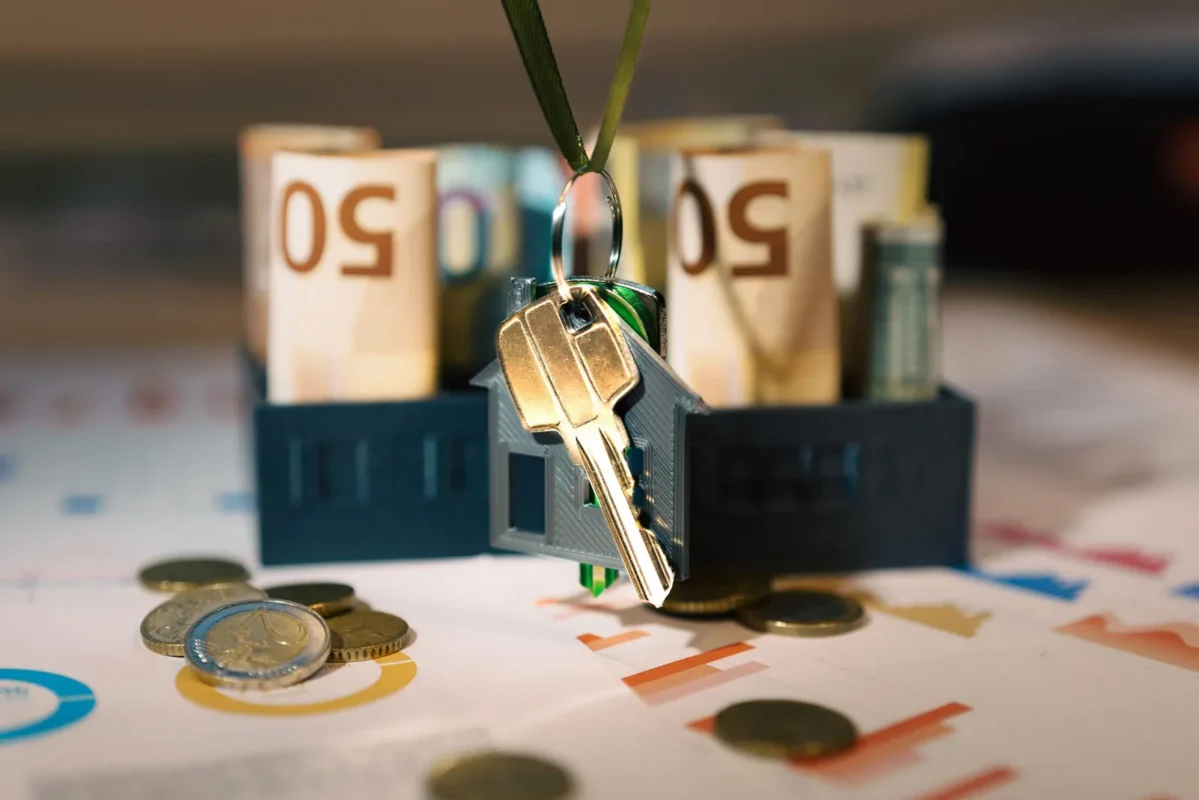 House keys hanging over a model house filled with rolled cash