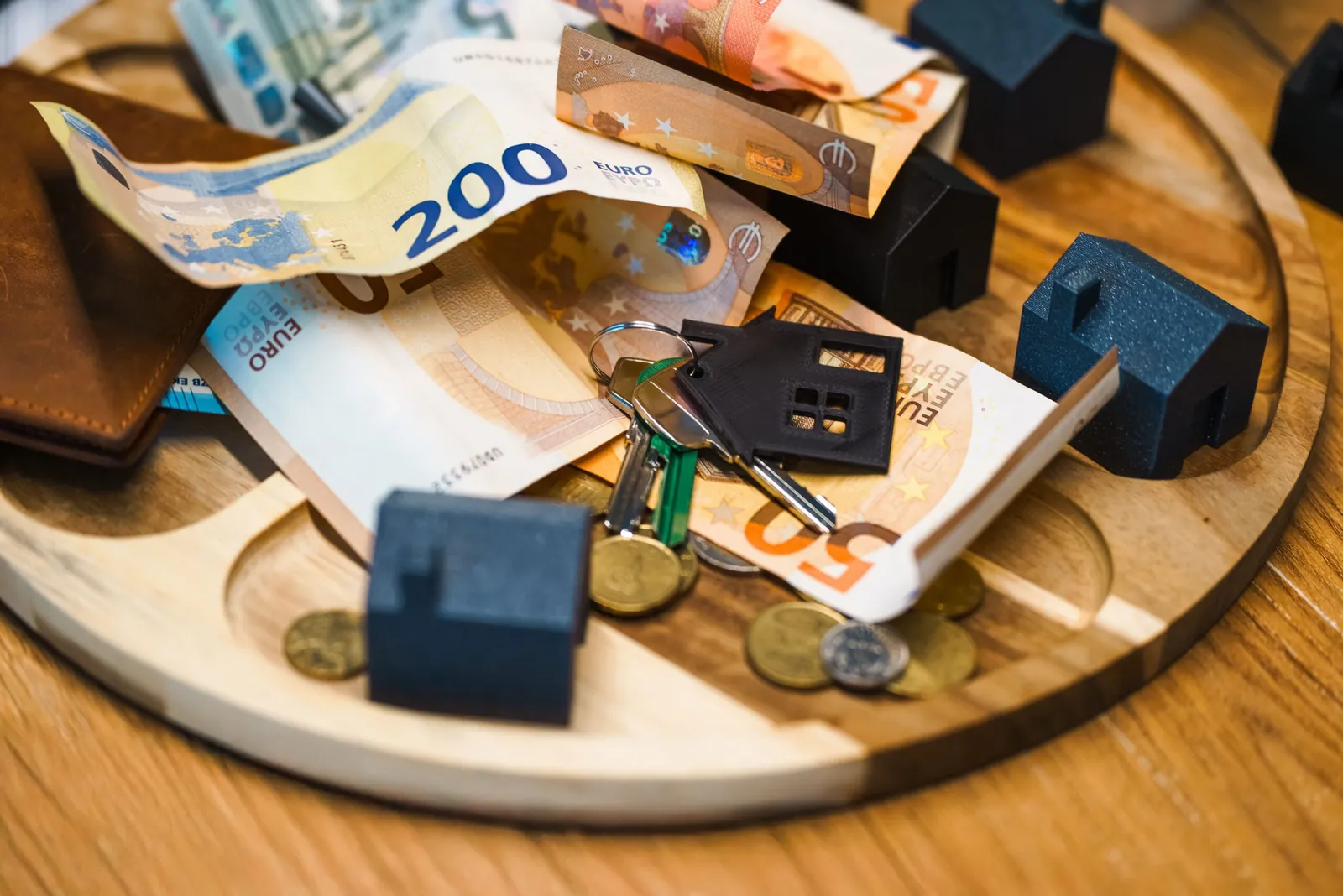 Euro notes, coins and model houses on a wooden tray