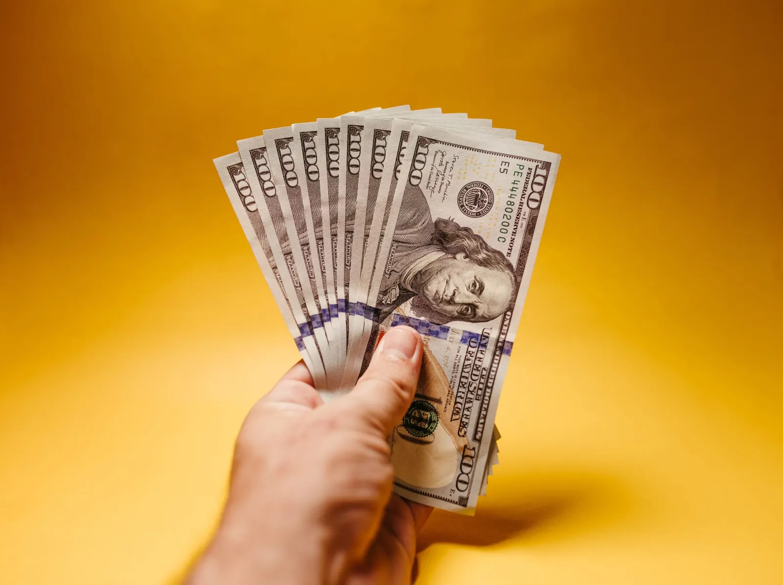 Hand holding a fan of US hundred-dollar bills
