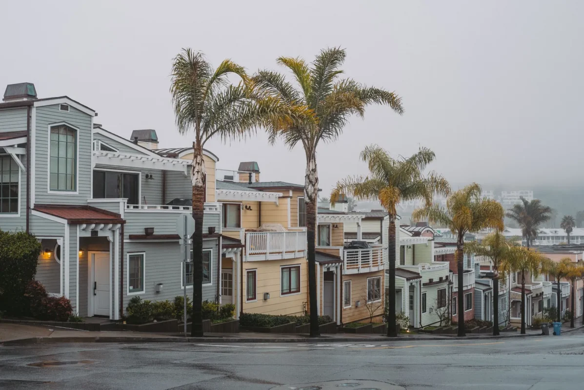 Row of two-story beach-style houses with palm trees on a foggy street