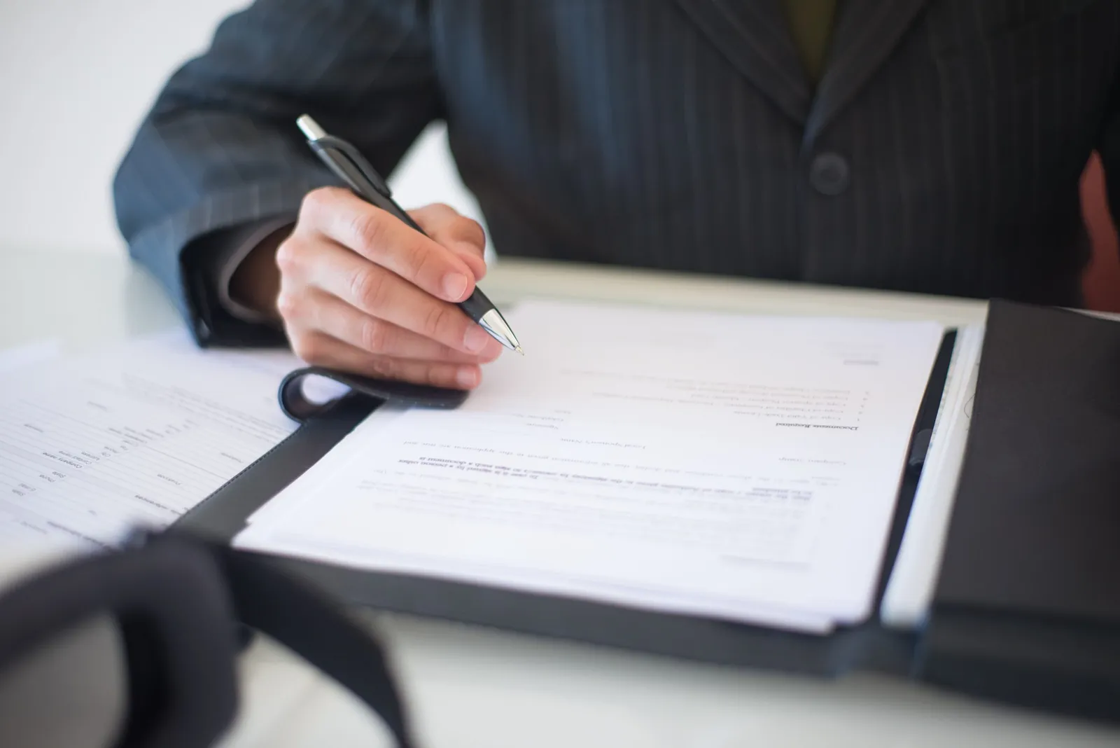 Person signing a document in a leather folder