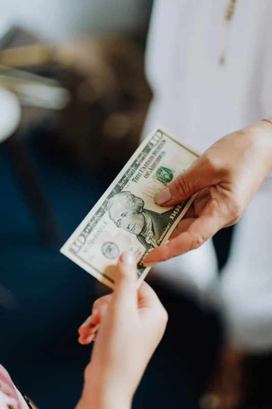 Hand passing a ten-dollar bill to another person