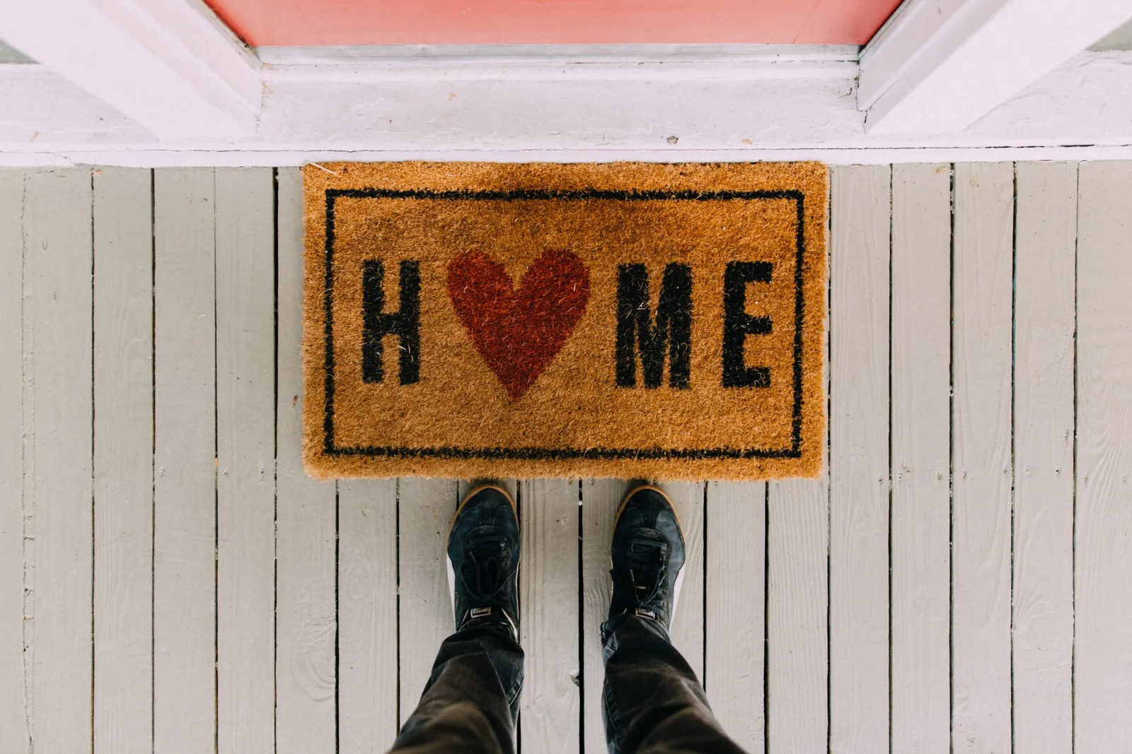 Person standing on a 'HOME' doormat with a heart