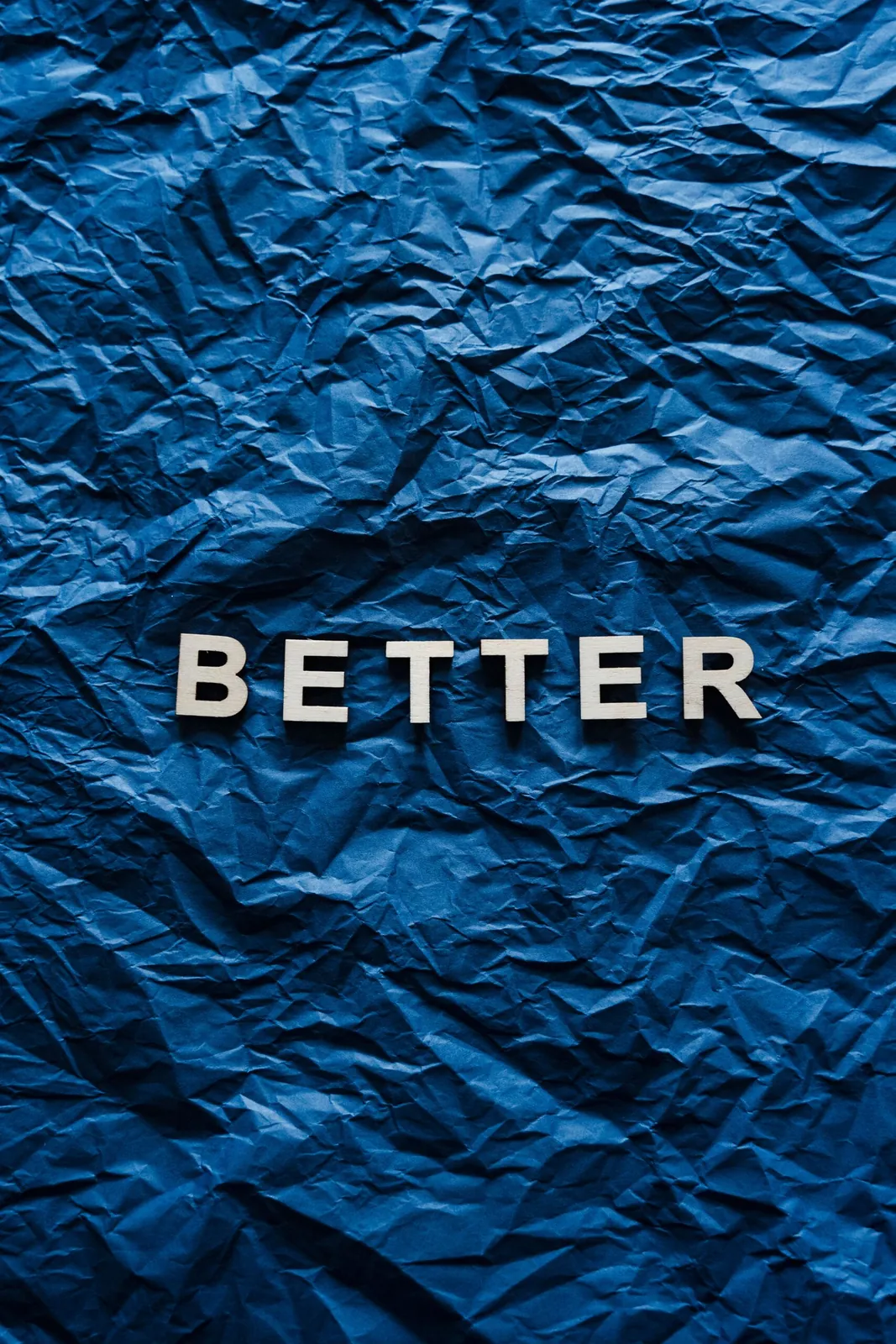 The word 'BETTER' on crumpled blue paper