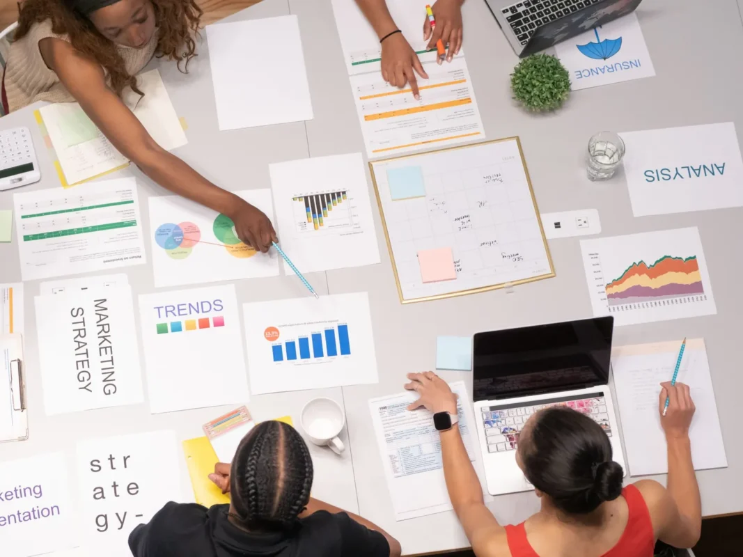 Team working over marketing charts and papers on a table, seen from above