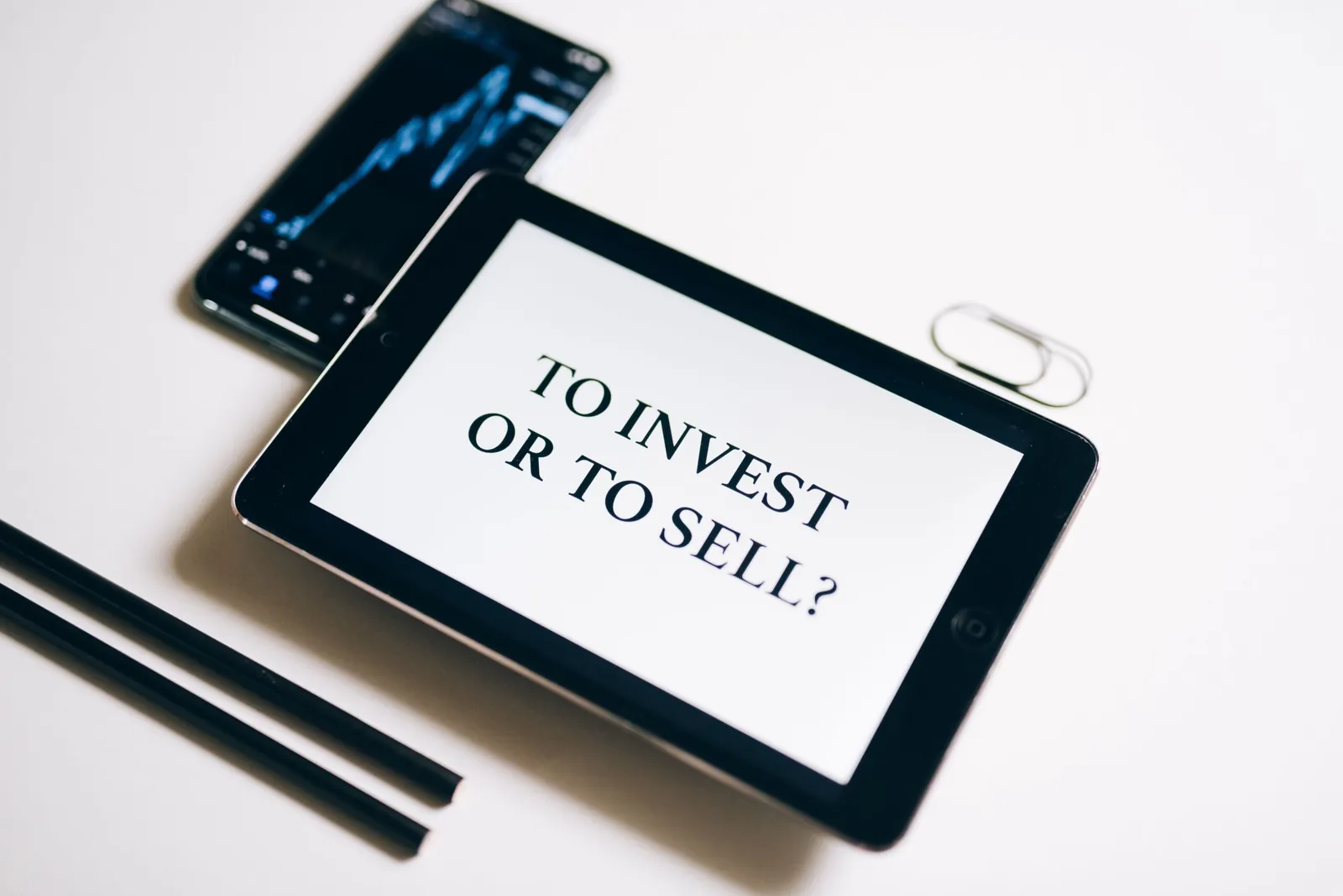 Tablet displaying 'To invest or to sell?'