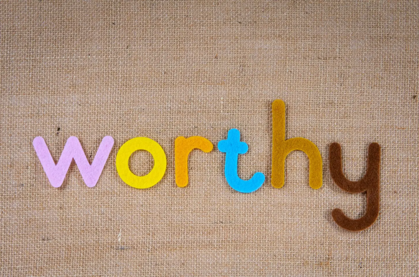 Colorful letters spelling 'worthy' on burlap