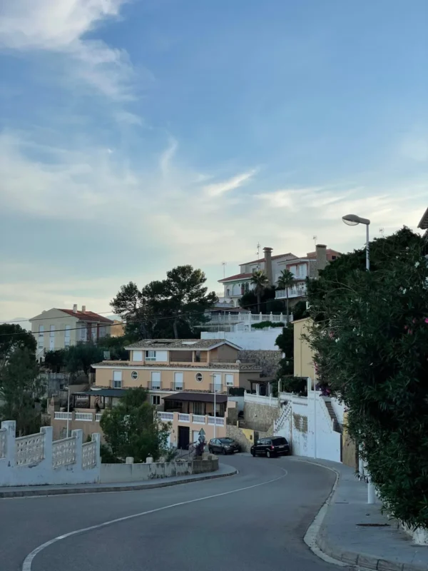 Residential street curving uphill past homes at dusk