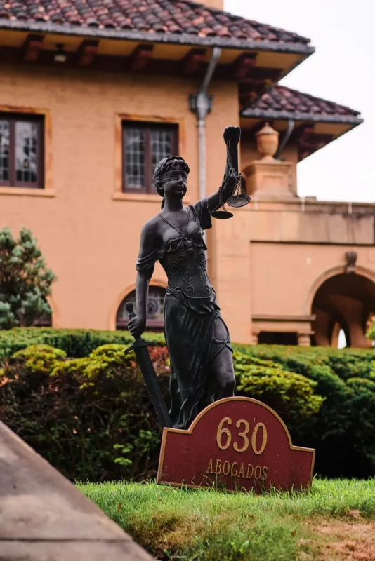 Lady Justice statue outside a Spanish-style building with a '630' address sign
