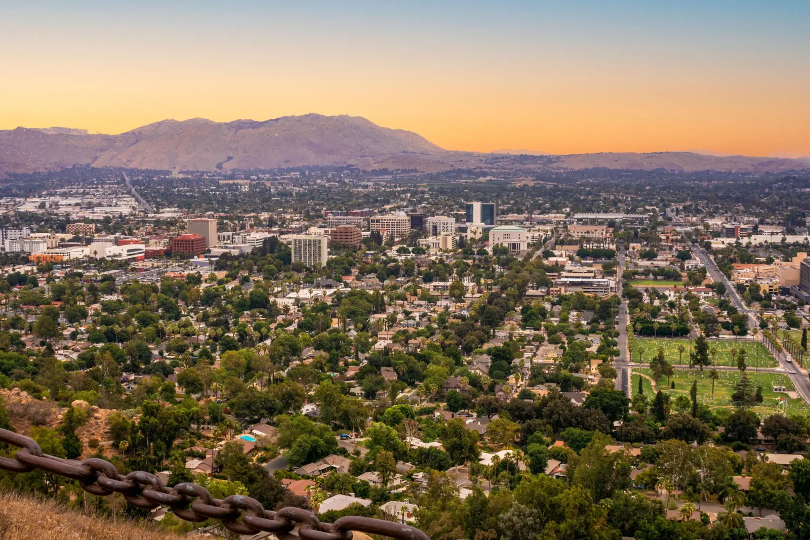 Tree-filled suburban city and low-rise downtown at sunset with mountains in the distance