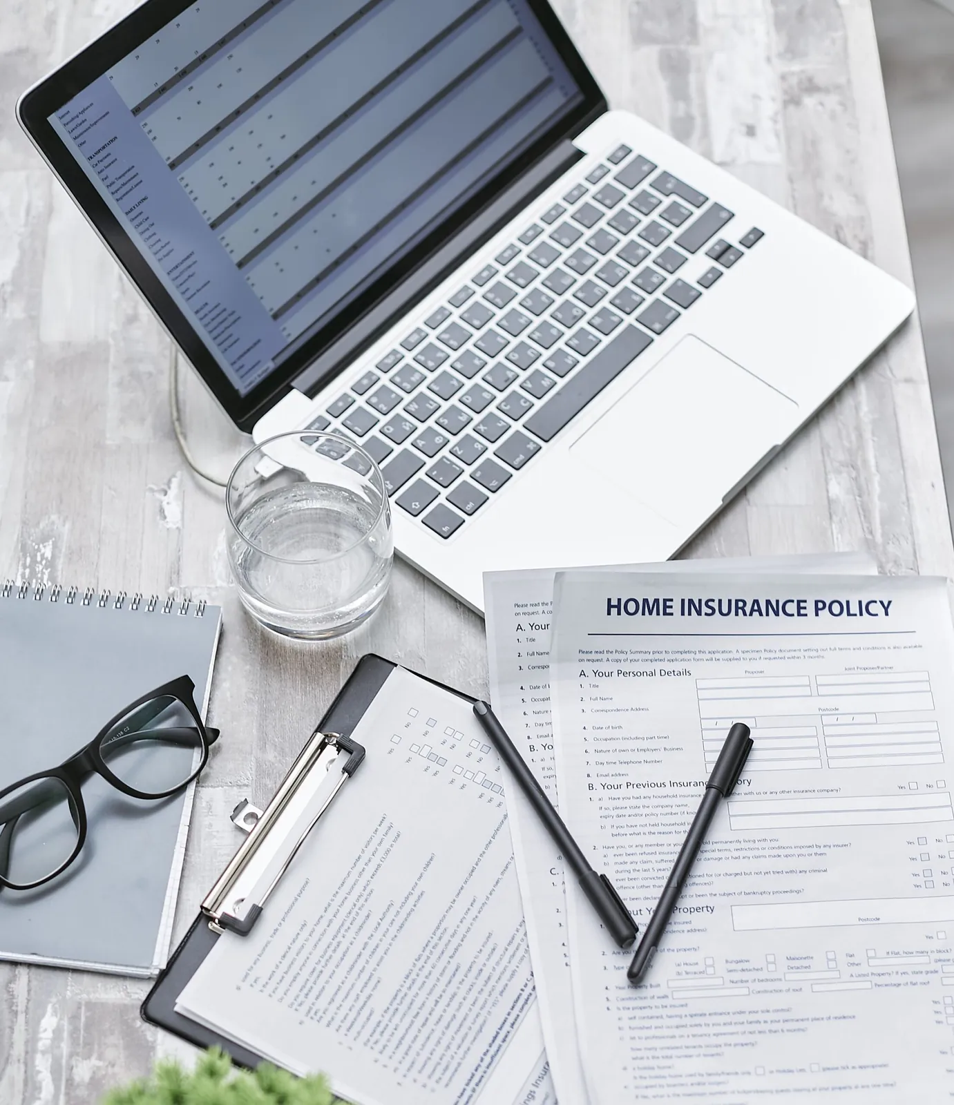 Home insurance policy form beside a laptop and glasses