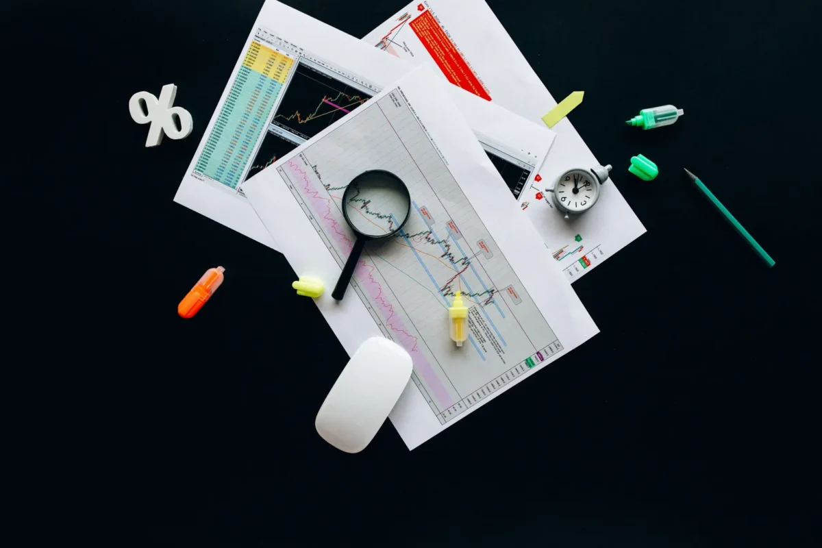 Overhead view of documents, magnifying glass and pins on a dark desk