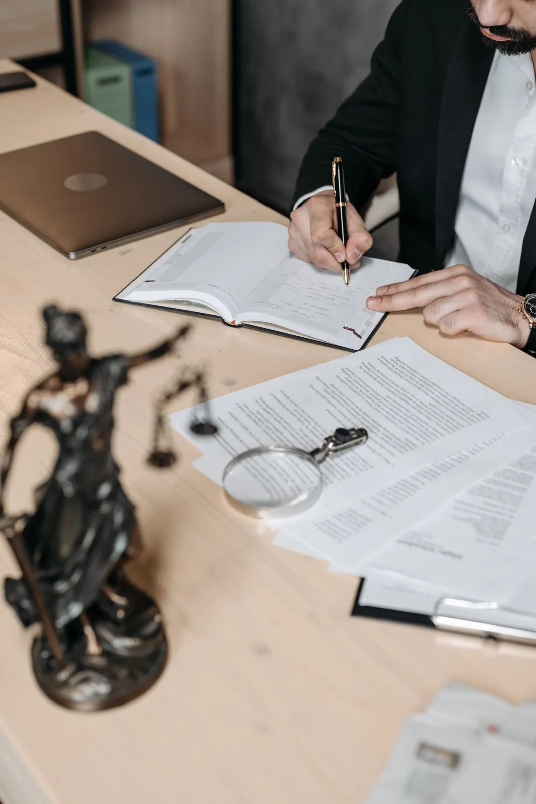 Attorney writing notes beside a Lady Justice statue