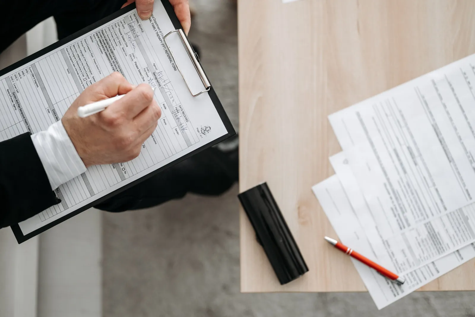 Two people filling out paperwork on clipboards