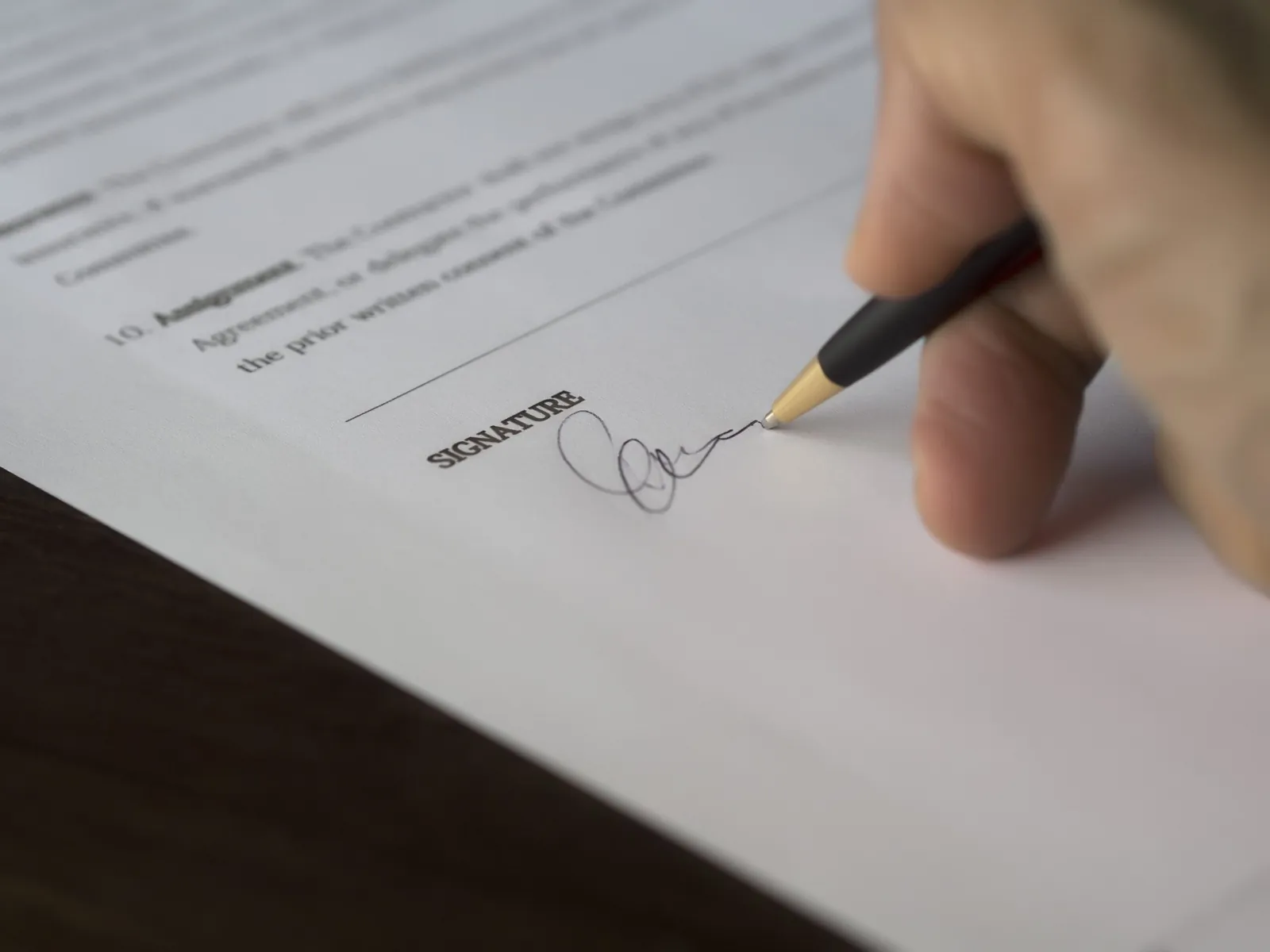 Person signing a document with a pen