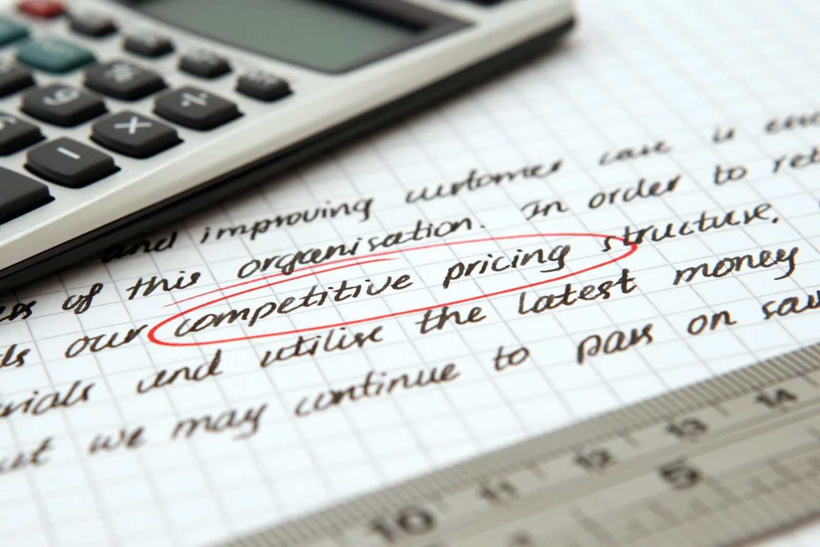 Calculator over handwritten notes about competitive pricing