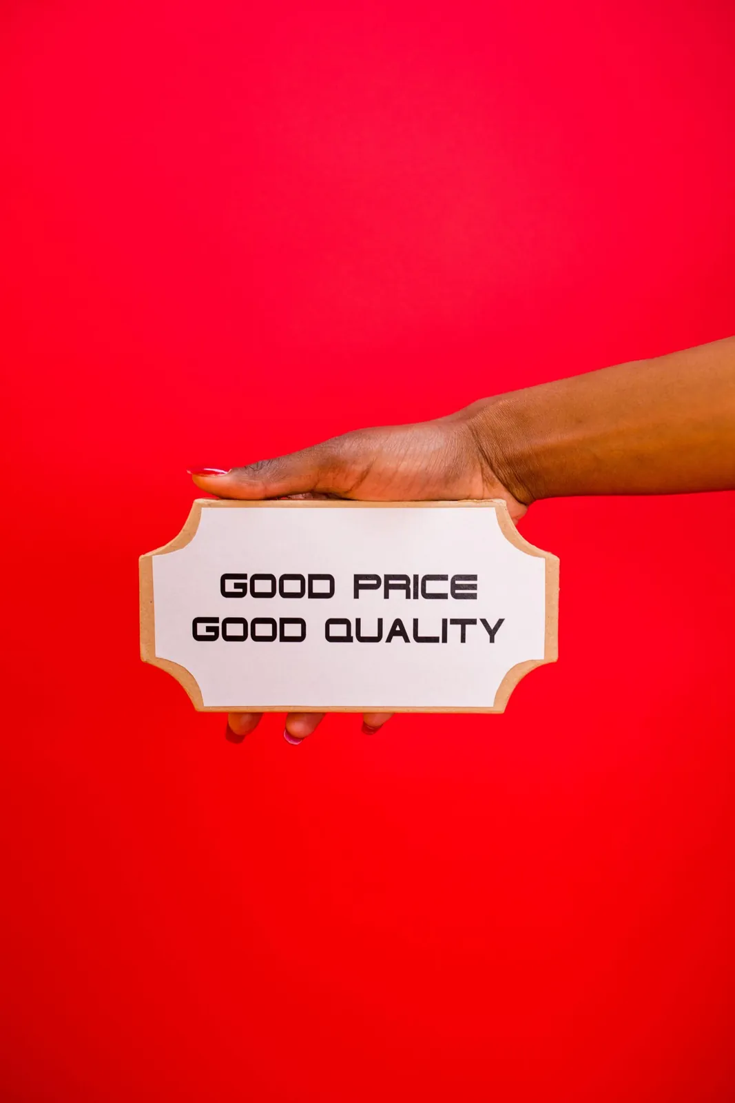 Hand holding a 'Good price, good quality' sign on a red background