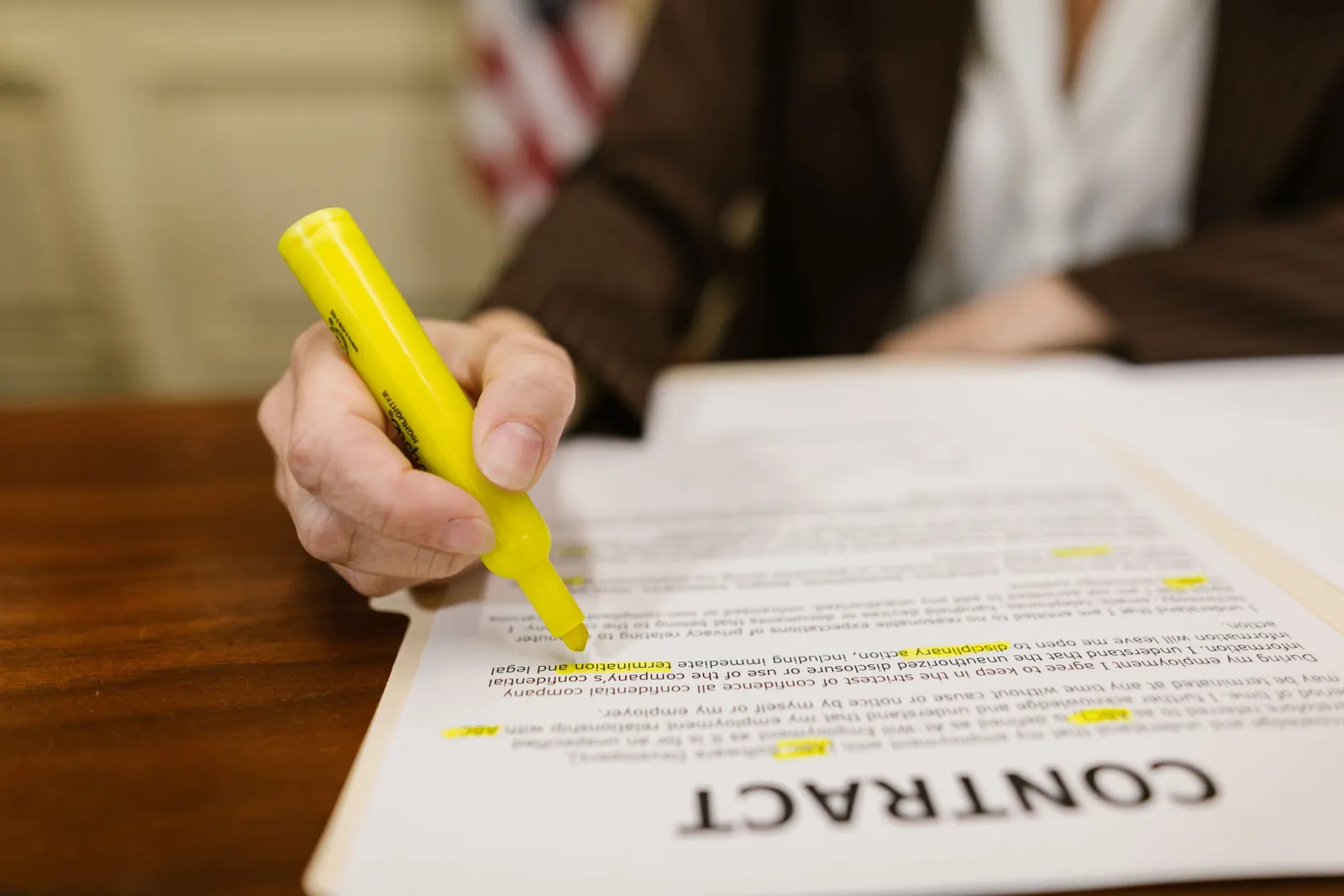 Hand highlighting terms on a contract with a yellow marker