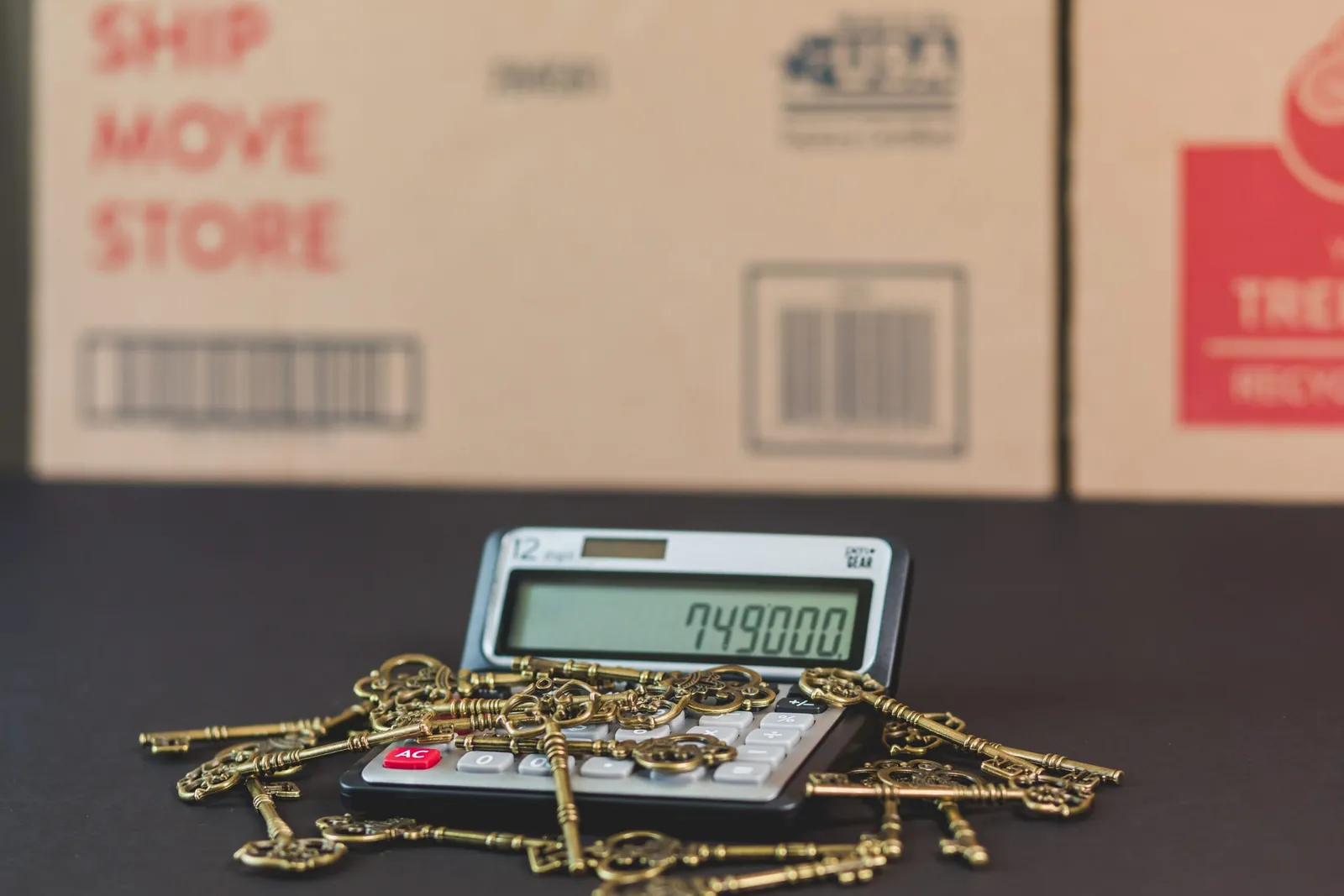 Calculator surrounded by keys in front of moving boxes