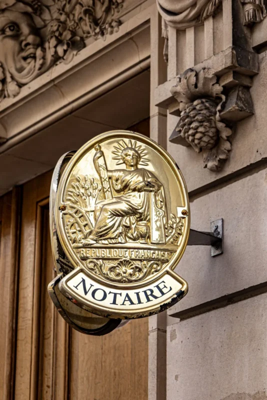 Ornate brass notary sign on a stone building
