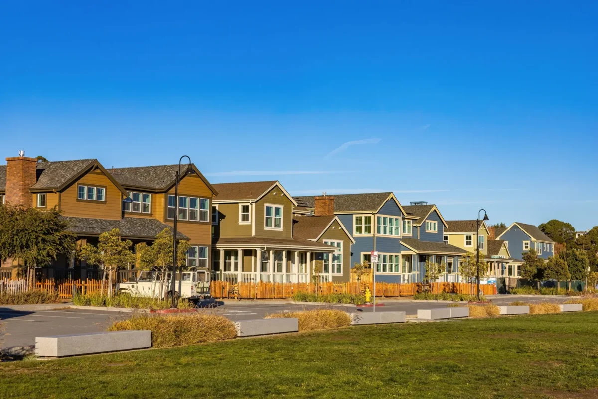 Row of two-story craftsman-style homes beside a lawn under blue sky
