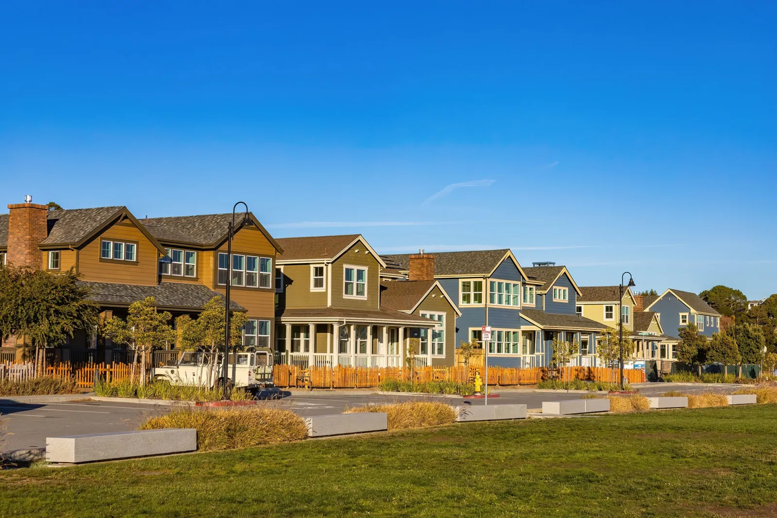 Row of two-story craftsman-style homes beside a lawn under blue sky