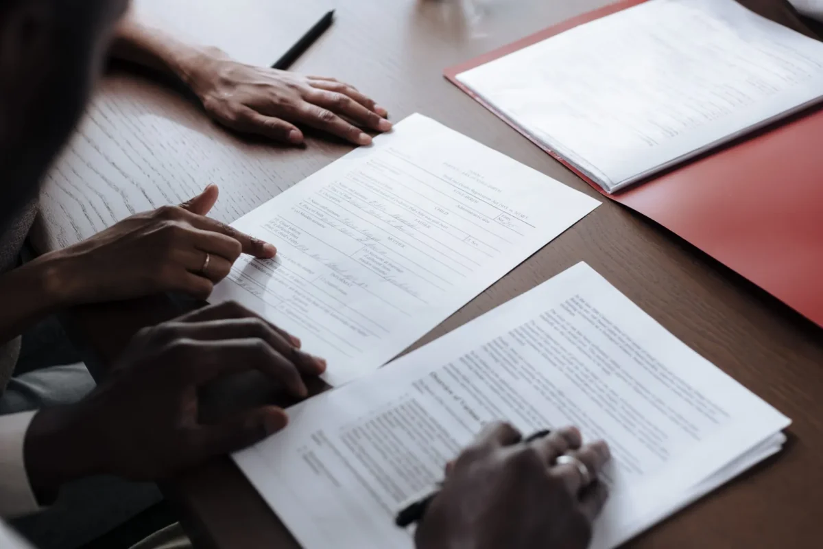 Two people reviewing and signing printed contract pages at a desk