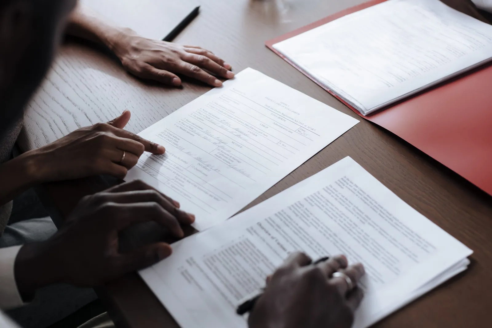 Two people reviewing and signing printed contract pages at a desk