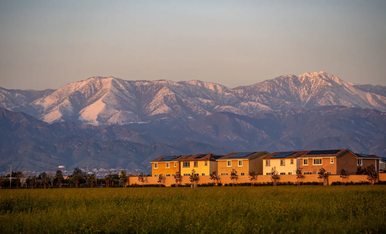 Row of two-story homes below snow-capped mountains at dusk