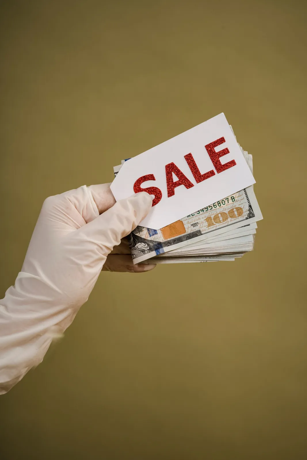 Gloved hand holding a 'Sale' tag and cash