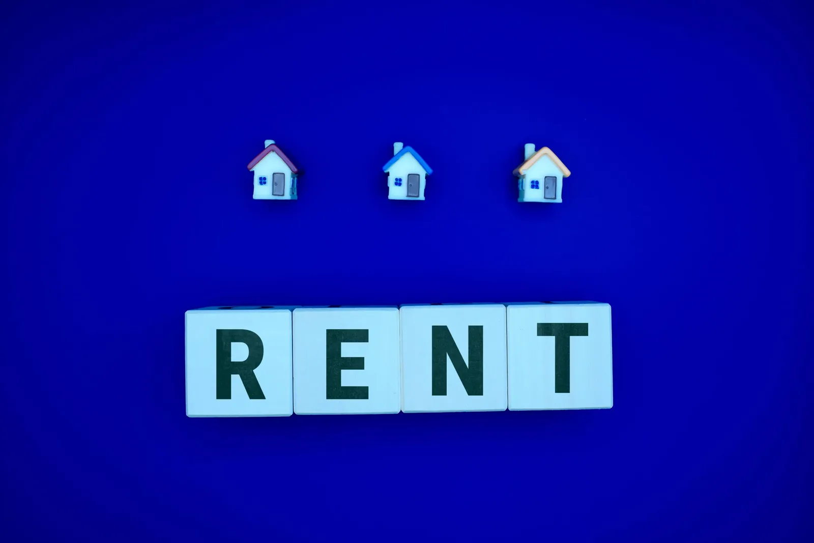 Letter tiles spelling RENT below three small house icons