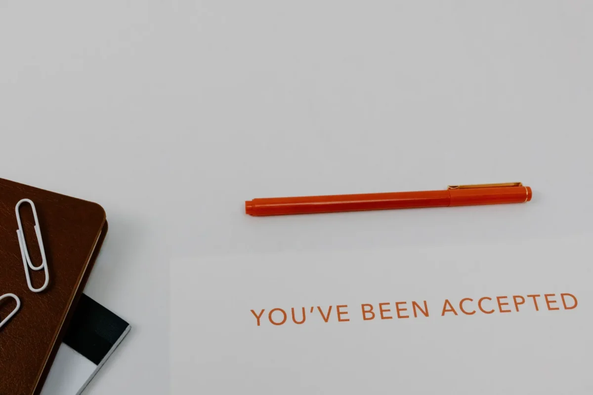 Paper reading You've Been Accepted beside an orange pen